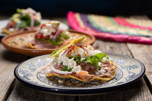 Traditional mexican ham toast also called tostadas with beans and cheese on wooden background