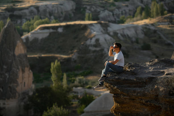 istock man sitting on cliff and looks into the distance. 1211913921