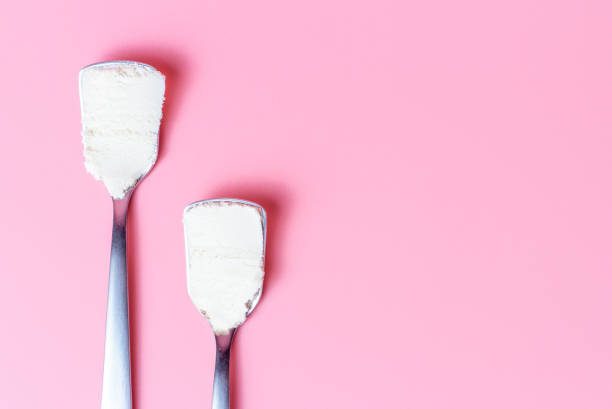 istock Two spoons with collagen powder on a pink background close up, copy space. 1211914078