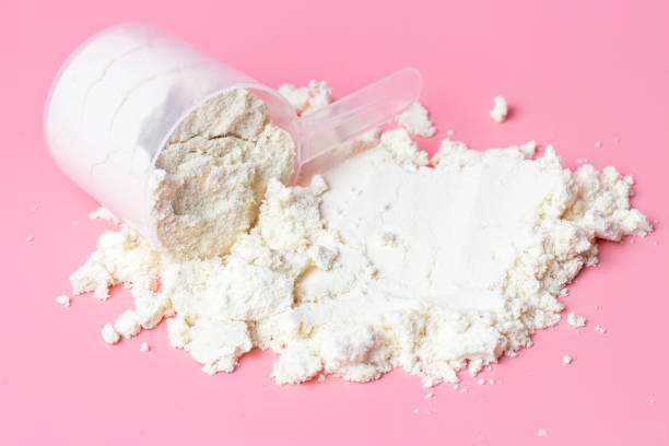 istock Scattered protein and measuring spoon on pink background top view. 1211914079