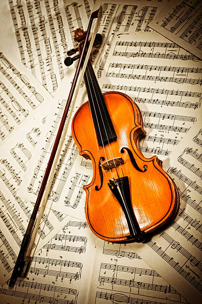 istock Old wood violin lying on musical notes 121191975