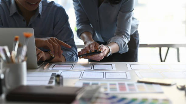 istock Cropped image of Ux Ui development team while working together at the modern working desk with computer laptop and information document flat lay on it. Collaboration in company concept. 1211921865
