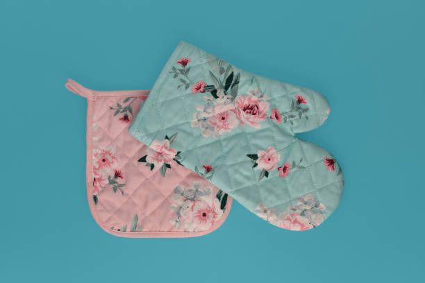 istock Kitchen glove potholders with flower patters isolated on a blue. 1211921868