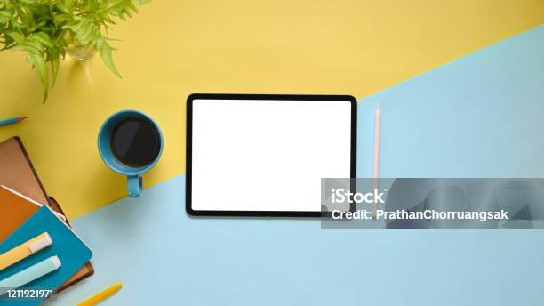 Top View Image Of Workspace With Flat Lay White Blank Screen Computer Tablet Coffee Cup Stylus Pen Marker Pens Stack Of Notebook And Potted Plant On Colorful Working Table Stock Photo - Download Image Now