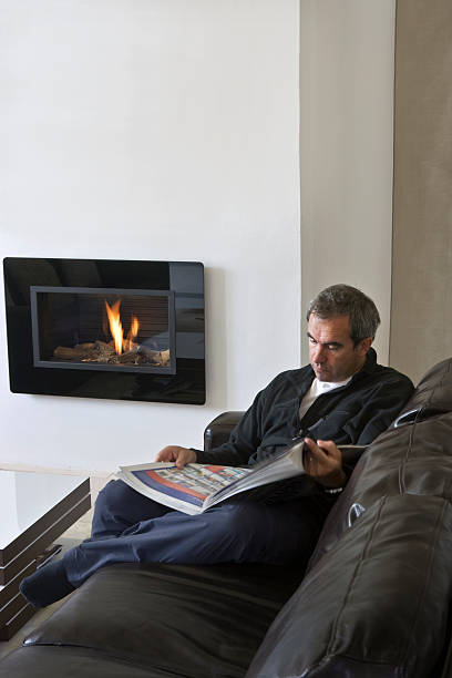 istock Male reading by contemporary fireplace 121192574