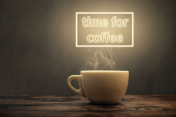 Steaming coffee cup under a glowing "time for coffee" sign A white coffee cup on a wooden surface. The cup gets illuminated by a "time for coffee" sign above it. tasse café stock pictures, royalty-free photos & images