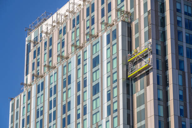 trabalhadores da construção não identificados em andaimes suspensos inspecionando / instalando revestimento em um edifício de alto nível em londres - uk scaffolding construction building activity - fotografias e filmes do acervo