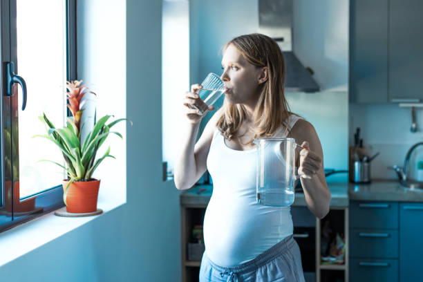 istock Pensive expectant mother drinking water at home 1211933809