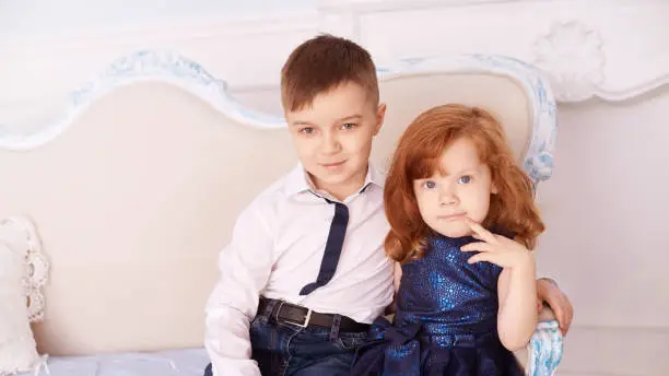 Brother and sister at winter Christmas studio. Two member of family. Happy child. Young couple posing