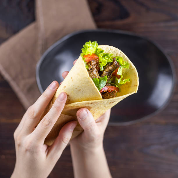 istock Burrito with beef in female hands 1211938014