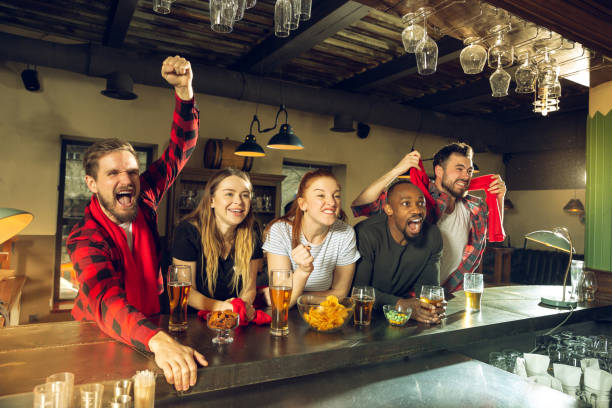 istock Sport fans cheering at bar, pub and drinking beer while championship, competition is going 1211944011