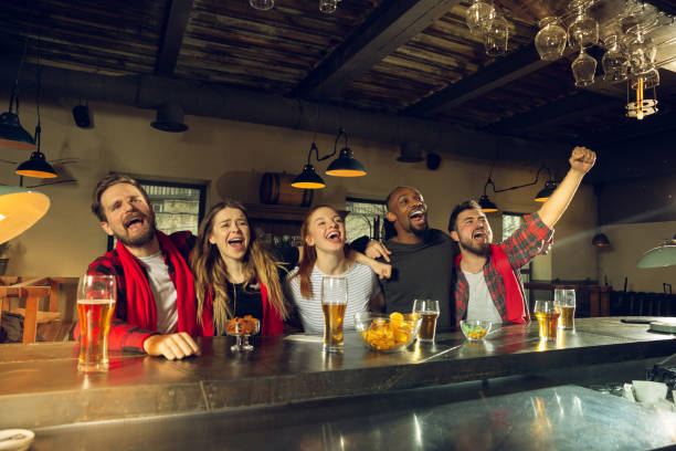 istock Sport fans cheering at bar, pub and drinking beer while championship, competition is going 1211944012