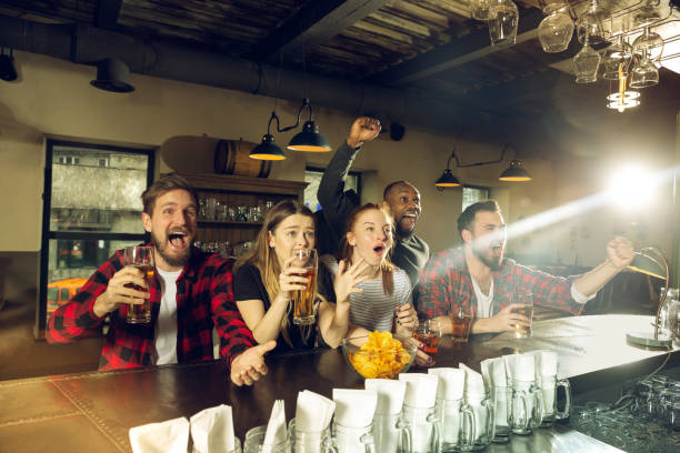 istock Sport fans cheering at bar, pub and drinking beer while championship, competition is going 1211944027