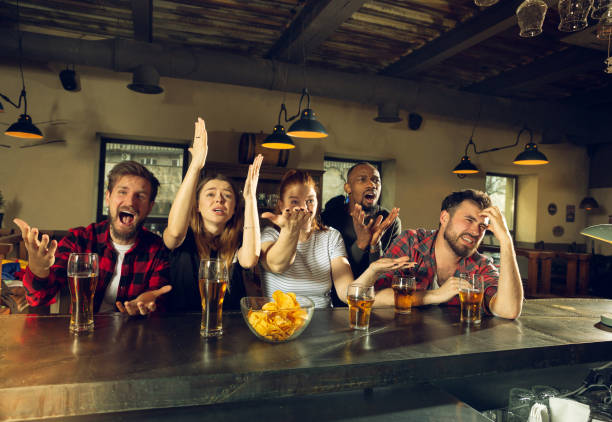 istock Sport fans cheering at bar, pub and drinking beer while championship, competition is going 1211944050