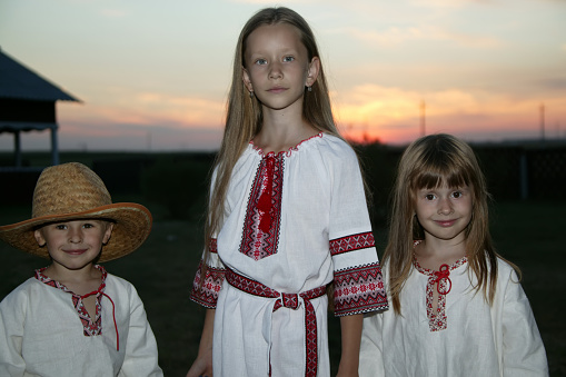 Slavic children in an embroidered shirt on a sunset background. Children are Ukrainian and Belarusians. People in national clothes.