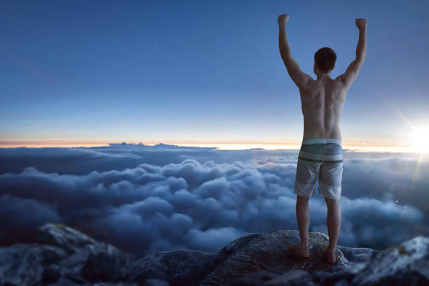 istock Man standing above the clouds with raised arms 1211948519