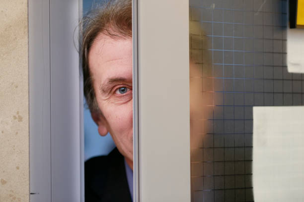 A man peeks out the door. The man is peeping.
