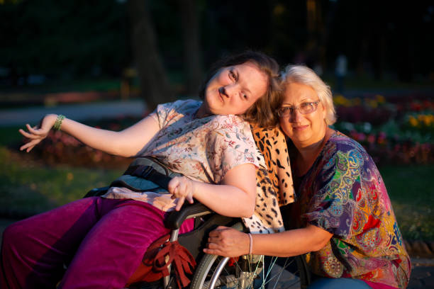 Well-groomed woman in a wheelchair with a guardian.Disabled woman with mom Well-groomed woman in a wheelchair with a guardian.Disabled woman with mom disabled adult stock pictures, royalty-free photos & images