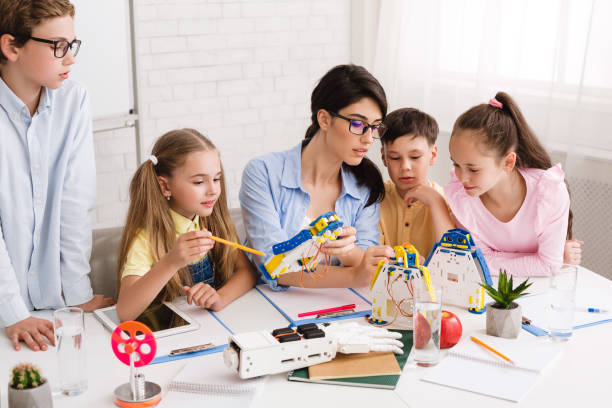 istock Robotics class. Teacher helping childern making diy robots 1211949540