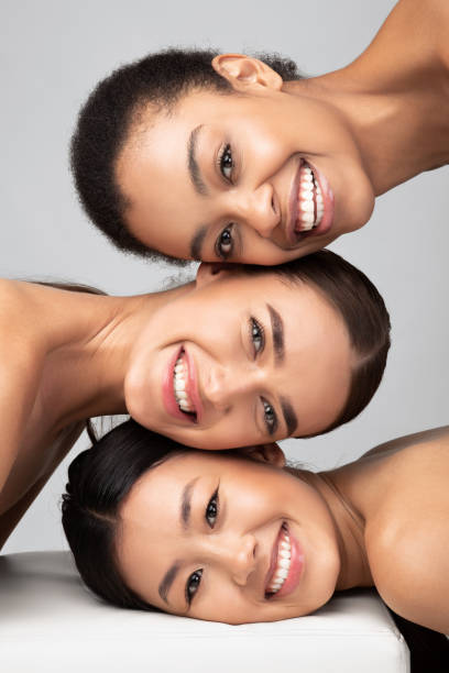 tres damas multiculturales posando sobre fondo gris, retrato de belleza, vertical - version 3 fotos fotografías e imágenes de stock