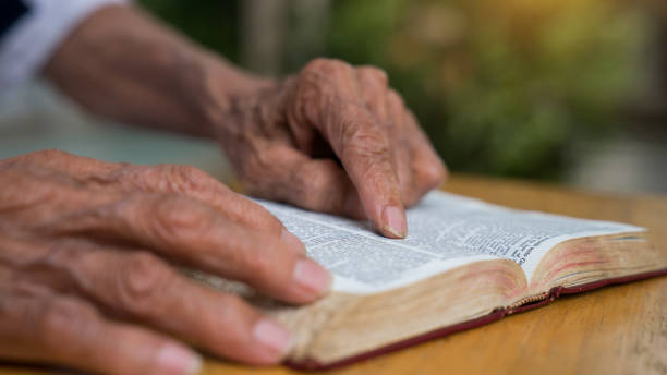 istock Old man reading her bible while sitting outside 1211950798