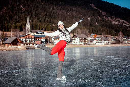 A woman gliding on her ice skates on a frozen lake surface.