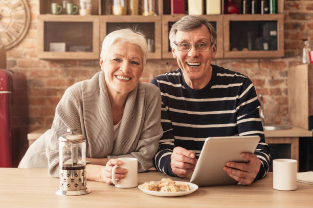 istock Happy aged couple with digital tablet in hands posing in kitchen 1211951594