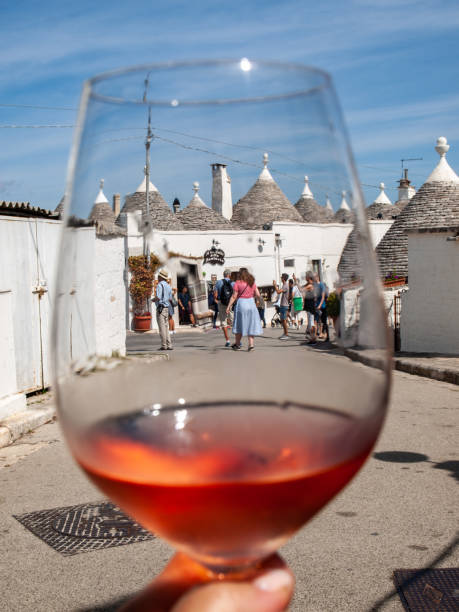 traditional white trulli house on Alberobello seen through a glass of rose wine, Apulia, Italy stock photo