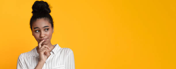 istock Doubtful afro girl thinking about something, looking away on yellow background 1211952472