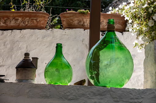 Alberobello, Italy - Septembet 16, 2019: Demijohn wine bottle at cafe in Trulli village in Alberobello, Italy.