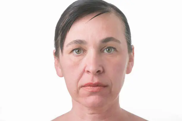 Photo of The face of a woman with wrinkles. Portrait of an elderly woman without treatment on a white background