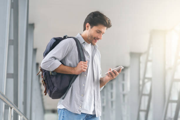 istock Man Traveller With Backpack Using Smartphone In Airport, Browsing Internet 1211954292