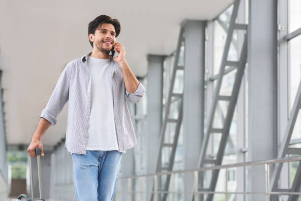 istock International Roaming. Young Man Talking On Cellphone While Walking In Airport 1211954321