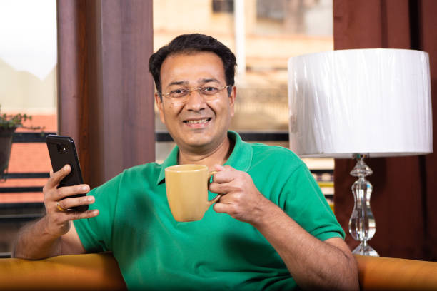 istock MATURE MAN RELAXING AT HOME HAVING COFFEE AND ON MOBILE 1211954391