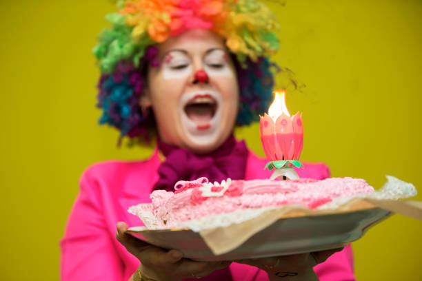 The clown puts out the cake.Birthday cake