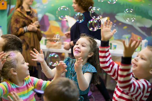 Children at the feast. Soap bubbles show. Children's party. To burst the soap bubble