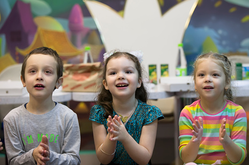 Enthusiastic children clap. Preschoolers are spectators. Admire the performance. Children's party