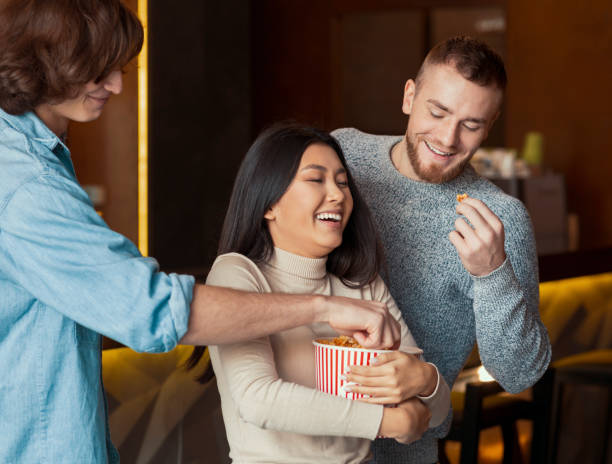 istock Friday evening. Joyful friends eating popcorn in cinema cafe 1211955598
