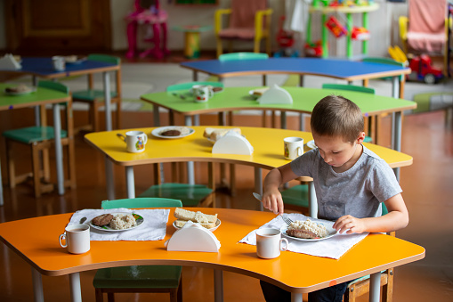 A child eats in kindergarten. A little boy at the table with food. Breakfast for children.