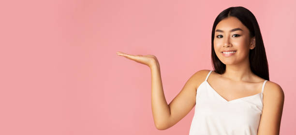 istock Chinese Model Girl Advertising Invisible Object Standing On Pink Background 1211956780