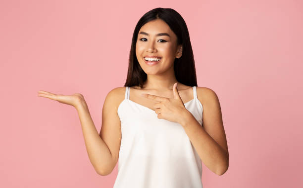 istock Asian Girl Holding Invisible Object Advertising It Posing, Studio Shot 1211956809
