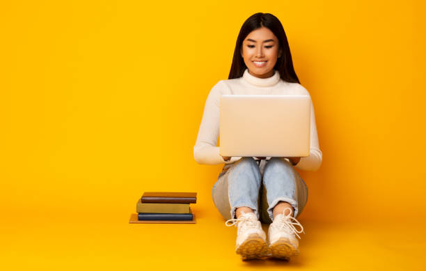 istock Asian Girl Using Laptop Studying Sitting On Floor In Studio 1211956863