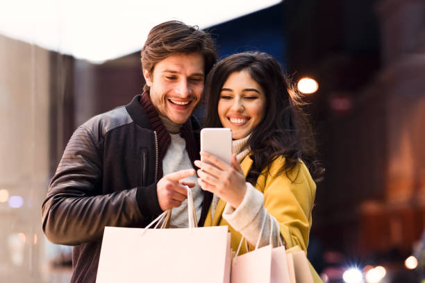 istock Loving couple using phone after shopping in mall 1211956882
