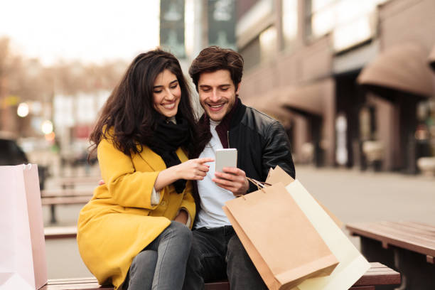 istock Loving couple using phone on the bench 1211956938