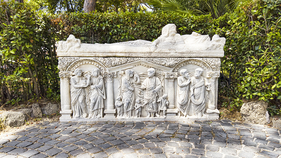 Ostia Antica, Italy - July 09, 2019: Beautiful marble decorated of ancient Roman white Sarcophagus, located in the Archaeological excavations of Ostia Antica,  Rome, Italy