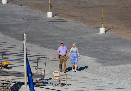 A senior Caucasian couple walking through the Mykonos Harbour area