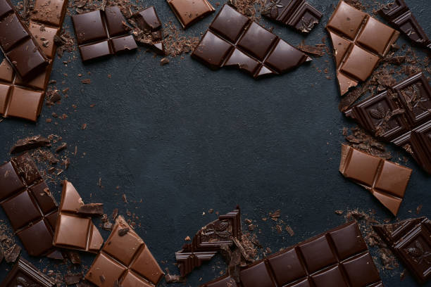 Slices of dark and milk chocolate Slices of dark and milk chocolate on a black slate, stone or concrete background. Top view with copy space. chocolate truffle making stock pictures, royalty-free photos & images
