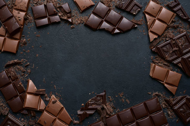 Slices of dark and milk chocolate Slices of dark and milk chocolate on a black slate, stone or concrete background. Top view with copy space. hot mix plant stock pictures, royalty-free photos & images
