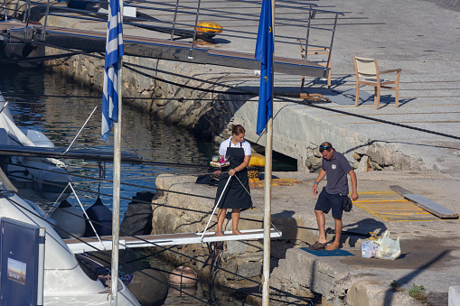 In Mykonos Harbour in Mykonos, Greece, a man prepares to get onboard while a woman watches on deck
