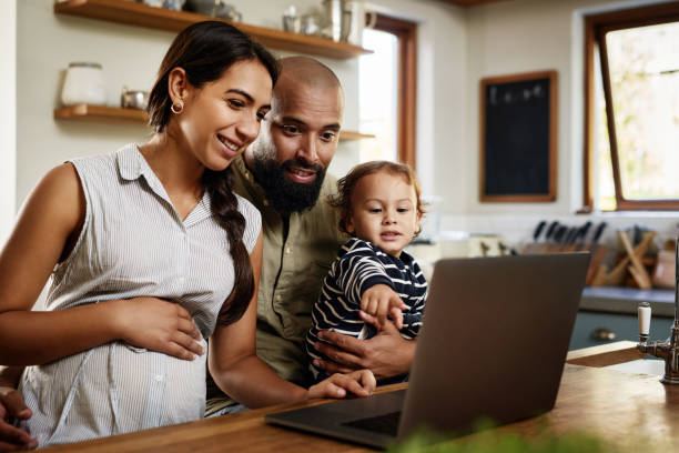 Make sure your family stays connected Shot of a happy young family using a laptop together at home young family stock pictures, royalty-free photos & images